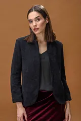 Chaqueta de corte entallado en color negro, confeccionada en un tejido suave con acabado ligeramente afelpado. Presenta un diseño minimalista sin botones, con cuello ligeramente elevado y mangas largas.
