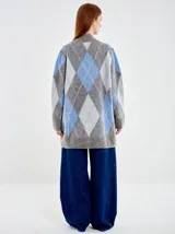 Saco largo de punto con diseño de rombos en tonos gris, azul y blanco. Presenta un calce amplio, silueta relajada y cierre frontal con un único botón. Confeccionado en una mezcla de fibras que incluye lana y poliamida con acabado texturizado.