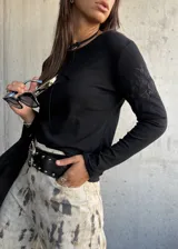 Remera de manga larga color negro, con cuello redondo y detalle de bordado floral sutil en el hombro. Confeccionada en algodón, presenta un corte ajustado y versátil.