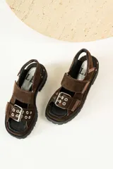 Sandalias negras de cuero con diseño de plataforma dentada, tiras ajustables con hebillas metálicas y detalle de tachas plateadas en el lateral de la suela.