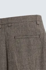 Pantalón de corte relajado con diseño de cuadros, confeccionado en tejido con lana. Presenta cintura con pliegues frontales, bolsillos laterales y bolsillos traseros de vivo, con cierre frontal de cremallera y gancho metálico oculto.