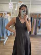 Vestido largo sin mangas, color beige claro, con escote en V y textura arrugada o arrugada, con terminación deshilachada en el ruedo.