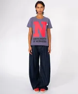 Camiseta de manga corta color marrón con efecto lavado y desgastado. Presenta una gran letra 'T' morada estampada en el centro, con el texto 'UNIVERSITY OF TENESSEE' debajo en color negro. Incluye apliques decorativos en el área del pecho.