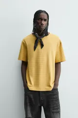 Camiseta de manga corta color crema, con cuello redondo y tejido texturizado con estructura.