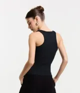 Musculosa básica de calce ajustado confeccionada en tejido rib acanalado. Presenta escote redondo y breteles medios, ofreciendo un diseño versátil y cómodo.