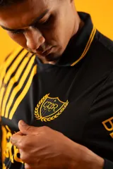 Camiseta de fútbol Puma del Club Atlético Peñarol, modelo Aniversario de manga larga. Diseño combinado con la mitad derecha a rayas verticales amarillas y negras, y la mitad izquierda totalmente negra con detalles en amarillo.