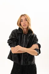 Campera de cuero sintético color negro, con cierre frontal, cuello clásico y bolsillos laterales con broches metálicos.