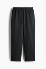 Pantalón de jogging negro de corte estándar, confeccionado en tejido de punto pesado. Presenta cintura elástica con cordón ajustable, bolsillos laterales y diseño de piernas rectas.