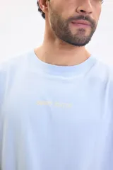 Remera celeste de manga corta y cuello redondo, con gran estampado en la espalda de un sol, ondas y diseño a cuadros con el texto "SUNSET STATION".