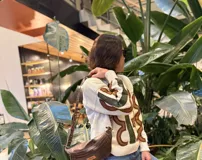 Sweater de lana merino en color crudo, con diseño de apliques de cuero en tonos marrón y verde oliva, cortados y bordados a mano. Presenta cuello redondo y mangas largas.