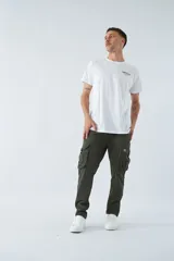 Pantalón cargo color beige, corte slim, con cierre y botón en la cintura, pasacintos, bolsillos cargo con botones y sin puños.