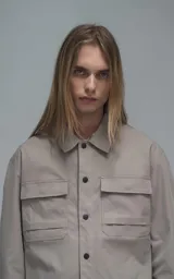 Chaqueta de corte regular crop confeccionada en microfibra pesada levemente elastizada. Presenta cuello volcado, cierre frontal con broches snap a tono y bolsillos delanteros con solapa.