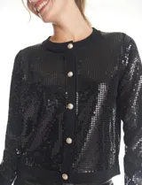 Cardigan de punto con frente bordado en lentejuelas negras. Presenta mangas largas y espalda en tejido rib, con cierre frontal de botones metálicos decorados.