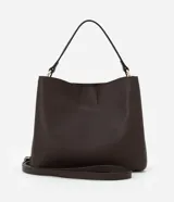 Bolso mediano color marrón oscuro, con doble asa corta y correa larga extraíble. Presenta textura símil cuero y detalle de aro dorado en el frente.