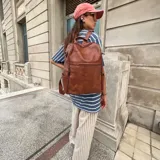 Mochila de cuero sintético marrón, amplia y resistente, con compartimento principal y bolsillos frontales y laterales con cierre.