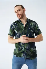 Camisa de manga corta con estampado botánico de hojas en tonos azul y blanco. Presenta cuello clásico, cierre frontal abotonado y corte slim.