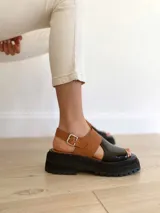 Sandalias de cuero color negro y camel, con plataforma track y hebilla ajustable.