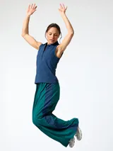 Conjunto compuesto por una chomba sin mangas azul marino de piqué con cierre frontal de botones y un pantalón ancho verde oscuro con franjas laterales azules.
