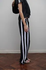 Pantalón de terciopelo negro con bandas laterales blancas, cintura elástica y botamanga recta.