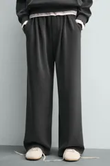 Pantalón jogger de corte wide fit confeccionado en tejido fluido con viscosa. Presenta un efecto lavado, cintura elástica ajustable con cordón, pliegues frontales, bolsillos laterales y un bolsillo trasero de plastrón.