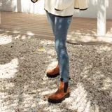 Bota de cuero color terracota, de caña media con elástico lateral y suela de neolite negra.