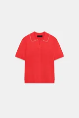 Top de punto rojo de manga corta, con cuello polo y escote en V. Presenta detalles de puntilla blanca en contraste con bordes ondulados en el cuello y los puños.