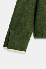 Chaqueta de punto color verde oscuro con cuello redondo y cierre frontal de botones. Presenta detalles de vivos en color crema en el cuello, la tapeta de botones y los puños.