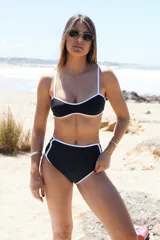 Conjunto de bikini negro con ribetes blancos, corpiño con breteles finos y bombacha de tiro alto.