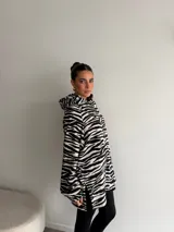 Canguro de viscosa con capucha, mangas largas abullonadas y diseño oversize con estampado animal print tipo cebra en tonos marrón y negro.