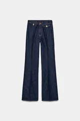 Jeans de tiro alto con corte flare y ajuste slim. Presenta trabillas en la cintura, bolsillos delanteros con detalle de botones metálicos y raya planchada a lo largo de las piernas. Cierre frontal con cremallera y botón.