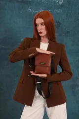 Phonebag pequeña color mostaza, confeccionada en cuero sintético, con solapa frontal y correa ajustable con logo de la marca.