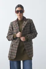 Blazer de corte relajado con estampado de cuadros tipo pied de poule en tonos rojizos y verdes. Presenta solapas clásicas en color azul oscuro y estructura definida.