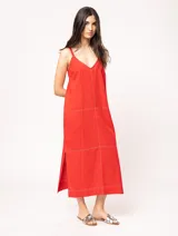 Vestido largo color crudo de lino, con silueta recta, escote en V, breteles anchos, detalle de elástico en la espalda y tajos laterales.