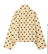 Chaqueta ligera de color amarillo con estampado de lunares negros, cuello alto, mangas largas anchas y cordón ajustable en el dobladillo inferior.