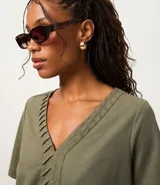 Blusa verde militar de piqué, corte slim, con escote en V y detalle texturizado en la vista delantera. Tiene mangas cortas.