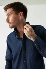 Camisa de jean azul con fit regular, manga larga, logo bordado, bolsillo y cartera con botones.