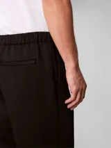 Pantalón de corte ceñido y largo al tobillo, confeccionado en tejido de tricot con cintura elástica. Presenta un diseño minimalista con logo de la marca bordado en el muslo.