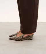 Zapato tipo slingback con estampado de piel de serpiente, puntera fina y taco anabela de 5 cm. Cuenta con tira ajustable en el talón con hebilla metálica.
