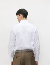 Camisa de vestir blanca de manga larga, con cuello clásico y cierre frontal de botones.