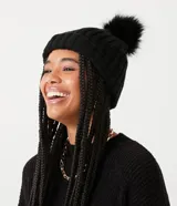 Gorro de punto acanalado en color blanco, con diseño de bajo plegado y pompón superior a tono.