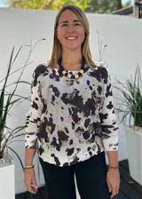 Sweater de punto con diseño estampado tipo animal print de vaca en tonos blanco, negro y detalles metalizados dorados. Presenta cuello redondo, mangas largas y corte holgado.