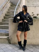 Vestido corto metalizado plateado, con escote en V, mangas largas acampanadas, cintura elastizada con cinturón y volados en el ruedo.