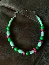 Collar corto con cuentas de cerámica, madera y acrílico en tonos de verde, verde menta y fucsia.