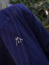 Pin plateado con forma abstracta.