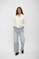 Camisa de corte clásico y silueta holgada, con cuello camisero, cierre frontal de botones y mangas largas con puños abotonados.