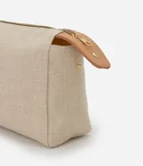 Neceser rectangular grande de color beige claro con textura de tejido canvas, cierre superior con cremallera dorada y detalles de cuero sintético color camel en los extremos.