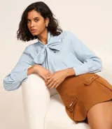 Minifalda marrón de polivelour con cierre lateral, solapas con hebillas y pliegues.