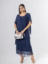 Vestido largo azul marino de seda italiana, con diseño de volados escalonados en la falda y una sobrecapa superior con mangas cortas amplias.