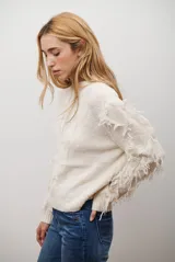 Buzo de punto color beige con cuello redondo, mangas largas con flecos decorativos y diseño de trenzas en el frente.