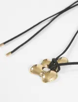 Collar con cordón marrón ajustable y dije de acero plateado con forma de flor irregular.